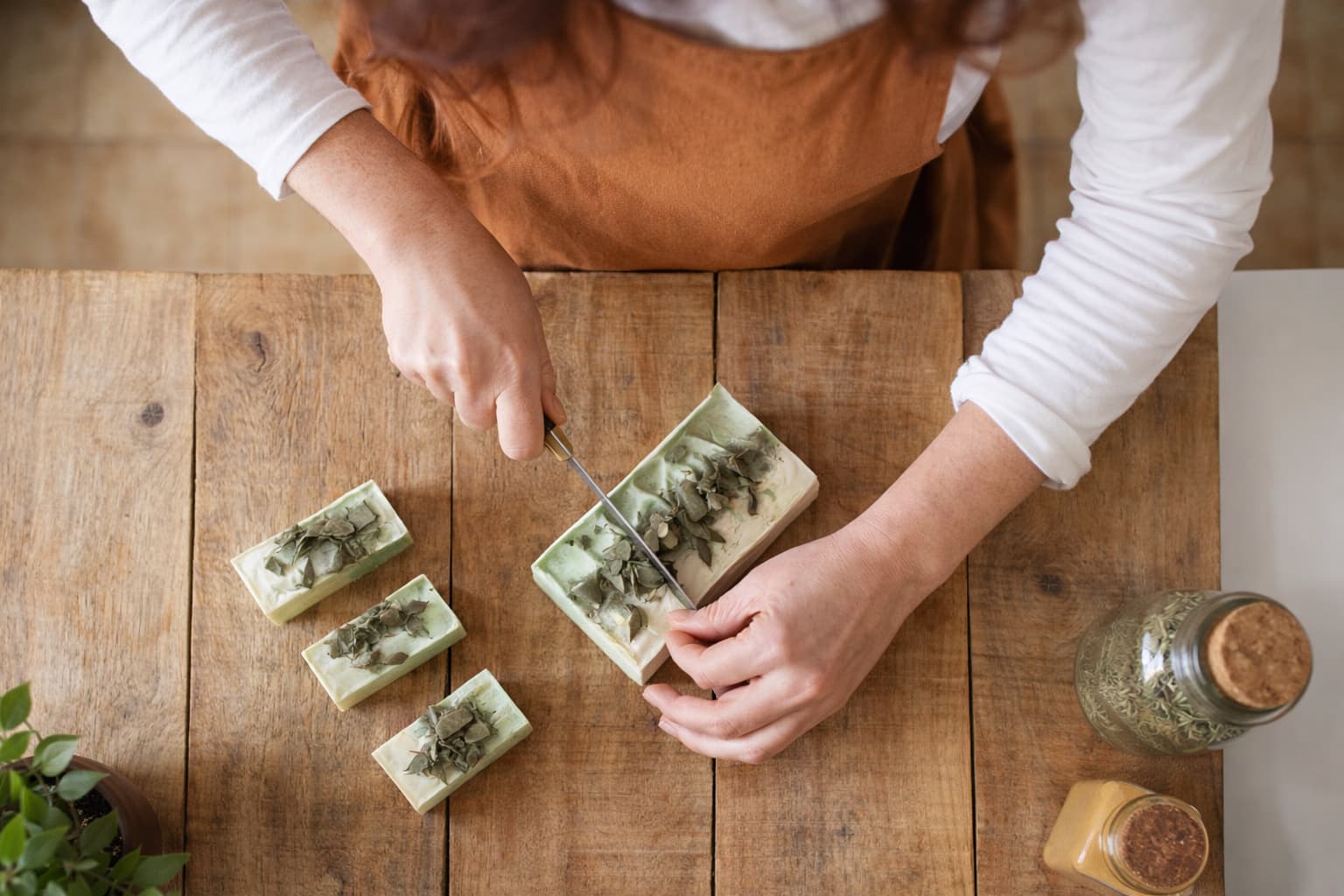 Handgemachte Naturseife wird auf einem Holztisch mit Kräutern geschnitten – Seife selber herstellen und verkaufen