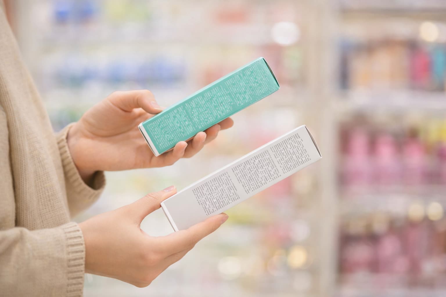 Hands comparing two cosmetic packages showing mandatory details — designing cosmetic labels yourself